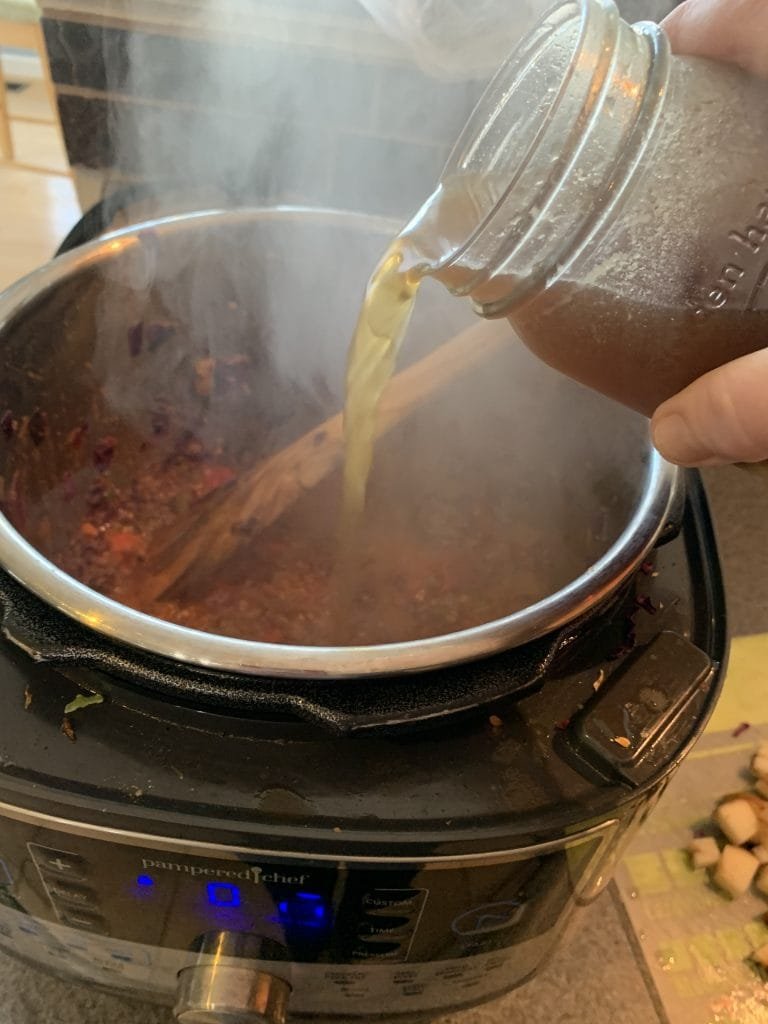 adding broth to soup